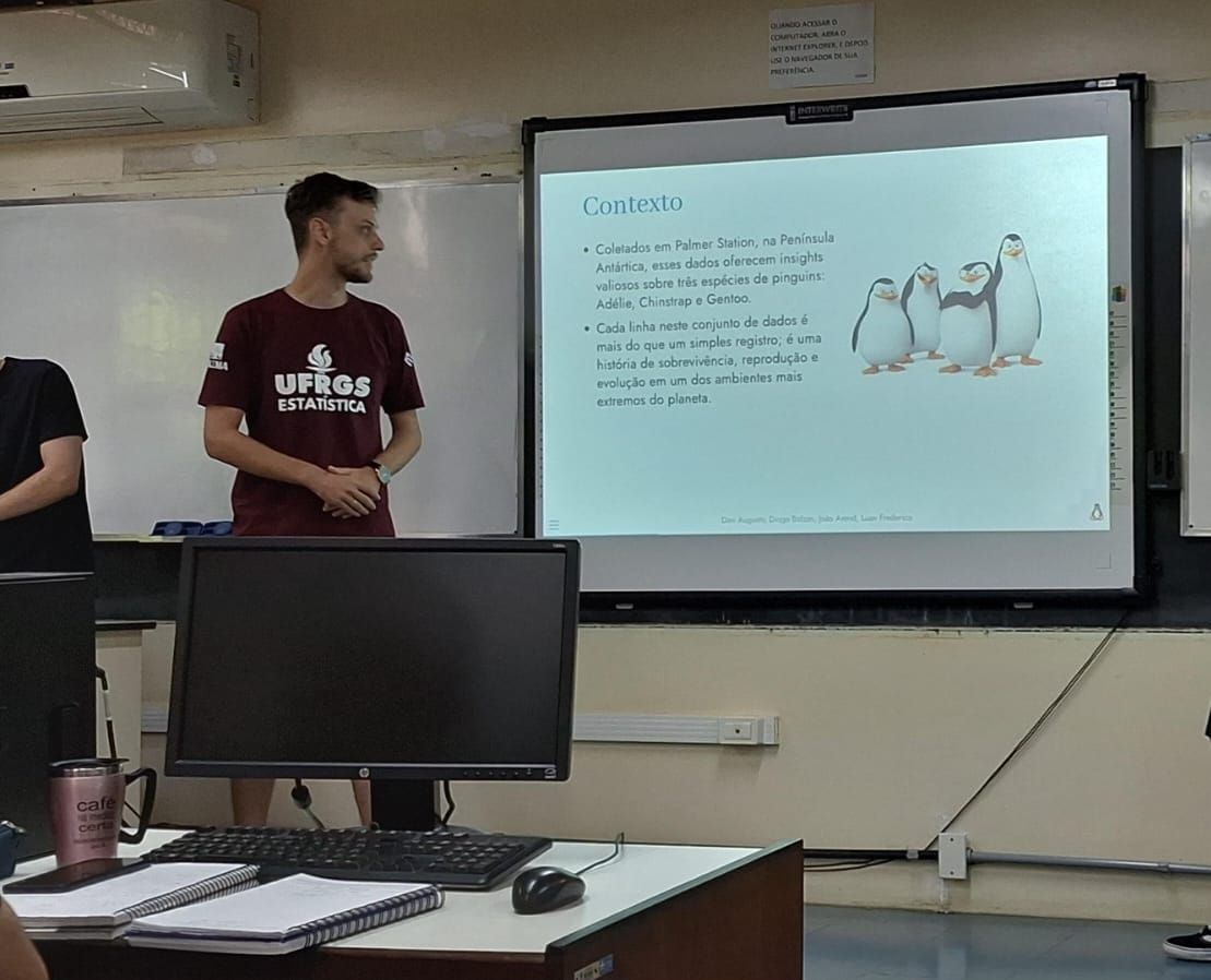 Davi, com a camiseta da Estatística UFRGS, apresentando em sala de aula o trabalho sobre o dataset Palmer Penguins